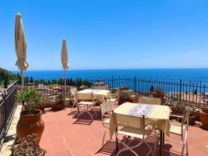 eine Terrasse mit Tischen und Stühlen und Meerblick in der Unterkunft Hotel Isabella in Taormina