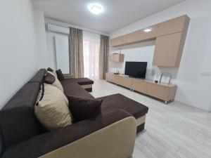 sala de estar con sofá marrón y TV en Apartament Moghioros Park Residence DUM1, en Bucarest