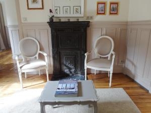 two chairs and a table in a living room with a fireplace at Chambre d hôte : Louvre Elegant Apt Suite in Paris