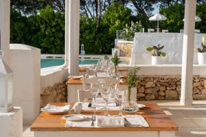 een houten tafel met wijnglazen op een patio bij Baglioni Masseria Muzza in Otranto