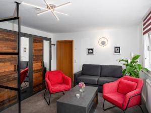 ein Wohnzimmer mit einem Sofa und zwei roten Stühlen in der Unterkunft City Appartements Arnstadt in Arnstadt