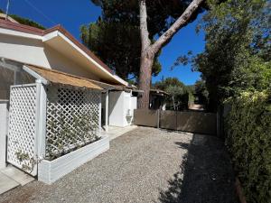 una recinzione bianca accanto a una casa con un albero di Punta Ala - Tra mare e natura a Punta Ala