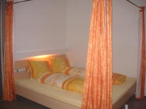 ein Bett mit zwei Kissen und einem orangenen Vorhang in der Unterkunft Ferienwohnung Pali in Sankt Johann in Tirol