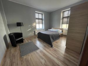 - une chambre avec un lit, une chaise et deux fenêtres dans l'établissement Apartamenty Trzciana, à Rzeszów