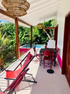 een patio met rode stoelen en een tafel op een terras bij Magnifique Villa Bauhinia, Piscine vue mer in Sainte-Luce