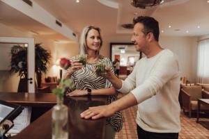 een man en een vrouw aan een toonbank met bloemen bij Hotel Summerhof in Bad Griesbach