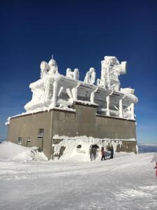 a building covered in snow with people in front of it at Apartmán Jeleň Chopok Juh-Trangoška in Tale