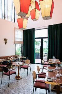 a restaurant with tables and chairs and green curtains at La Maison Palmier Abidjan, a Member of Design Hotels in Abidjan