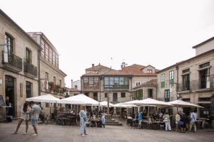 een groep mensen die rond een binnenplaats lopen met tafels en parasols bij Hotel Restaurante Rúas in Pontevedra