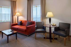 a living room with a red couch and two chairs at Sonesta Chicago O'Hare Airport Rosemont in Rosemont