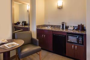 a hotel room with a kitchen with a sink and a table at Sonesta Chicago O'Hare Airport Rosemont in Rosemont