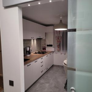 una cucina con armadietti bianchi e servizi igienici di Hermann Apartment a Cluj-Napoca