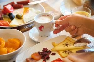 une personne tenant une tasse de café sur une table avec de la nourriture dans l'établissement Continental Forum Constanta, à Constanţa