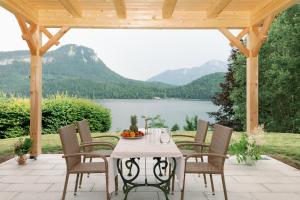 een tafel en stoelen op een patio met uitzicht op een meer bij Villa Frischmuth am See in Altaussee