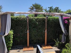 a pergola in a garden with a hedge at Nora Guesthouse Rooms and Villas in Pula