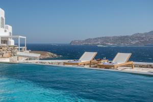 - une piscine avec 2 chaises longues et l'océan dans l'établissement Mykonos Esti Luxury Villas, à Agios Ioannis Mykonos