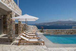 - un ensemble de chaises longues et d'un parasol à côté de la piscine dans l'établissement Mykonos Esti Luxury Villas, à Agios Ioannis Mykonos