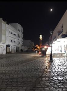 a cobblestone street at night with a clock tower at Cosy Appart - Central & Near main interest points in La Marsa