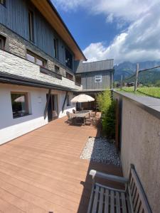 eine Terrasse mit einem Tisch, Stühlen und einem Sonnenschirm in der Unterkunft Mona Apartment in Going