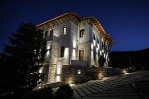 Un grand bâtiment blanc avec des lumières allumées la nuit dans l'établissement KERCULLA Resort, à Gjirokastër