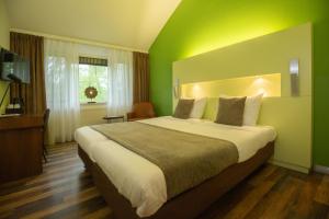 una camera da letto con un grande letto con una parete verde di 50|50 Hotel Belmont a Ede