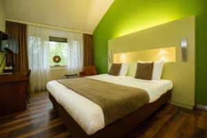 una camera da letto con un grande letto con una parete verde di 50|50 Hotel Belmont a Ede