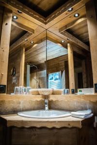 a bathroom with a sink and a large mirror at Les Chalets de la Serraz in La Clusaz