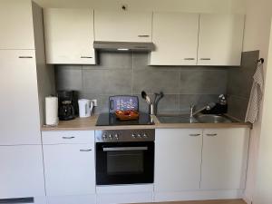 een keuken met witte kasten en een fornuis met oven bij Appartement 1 mit Küche und neuem Bad, frisch saniert in Friedrichskoog