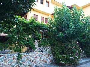 uma parede de pedra com árvores e flores em frente a um edifício em Vasileiou em Kala Nera