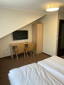 Habitación de hotel con escritorio y TV en GRACJA, en Warszawa