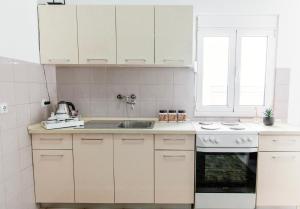 a white kitchen with white cabinets and a sink at Castello Apartments in Ulcinj