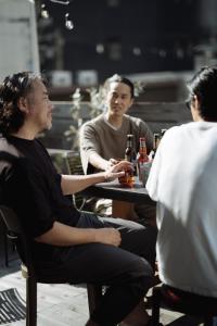 een groep mannen aan een tafel met flessen bier bij Good Neighbors in Kanazawa