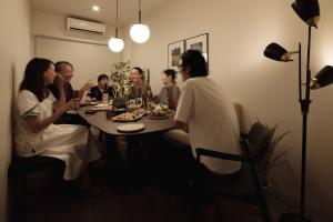 een groep mensen die rond een eettafel zitten bij Good Neighbors in Kanazawa