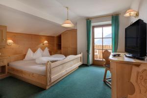 a bedroom with a bed and a tv and a window at Garni Ziernheld in Malles Venosta