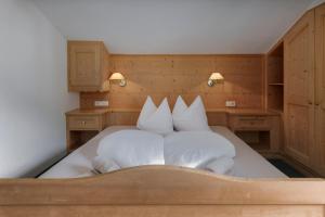 a bedroom with a bed with white sheets and pillows at Garni Ziernheld in Malles Venosta