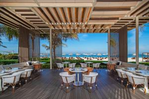 a restaurant with tables and chairs on a deck at The Oberoi Beach Resort, Al Zorah in Ajman 