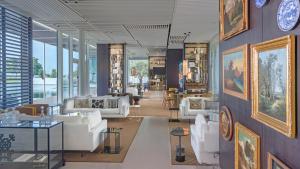 a living room with white furniture and a wall of windows at The Oberoi Beach Resort, Al Zorah in Ajman 