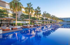 a hotel pool with chairs and umbrellas and palm trees at The Oberoi Beach Resort, Al Zorah in Ajman 