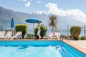 Una donna è in piedi sul bordo di una piscina di Hotel Splendid Palace a Limone sul Garda