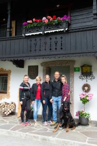 um grupo de pessoas e um cão em frente a um edifício em Riemenerhof em Fügen