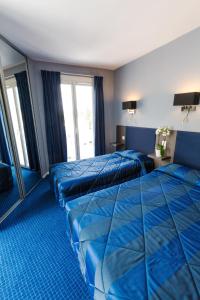 2 letti in camera d'albergo con lenzuola blu di Hôtel Irlande a Lourdes