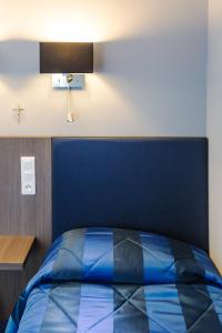 una camera con letto blu e testiera blu di Hôtel Irlande a Lourdes