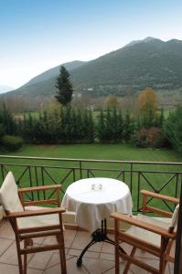 een tafel en 2 stoelen op een balkon met uitzicht op de bergen bij Aroanios Hotel in Klitoria