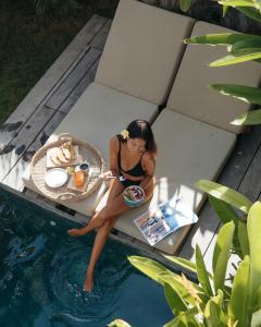 Eine Frau auf einem Tisch neben einem Pool in der Unterkunft Kalea Villas in Kuta Lombok