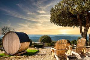 dos sillas y un barril sentado junto a un árbol en La Bastide De Tourtour Hotel & Spa, en Tourtour