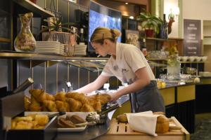 a woman preparing loaves of bread in a bakery at Studios Astra Hotel Vevey in Vevey