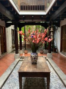 a vase with flowers sitting on a wooden table at Posada El Antaño in Antigua Guatemala