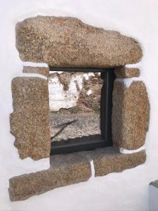 a window in a stone wall with a mirror at Azeite de Marvão, Olivoturismo casa Venda do Lagar in Marvão