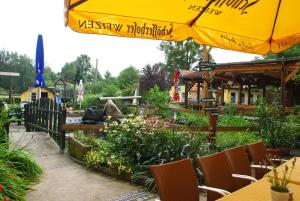 a garden with a yellow umbrella and chairs and flowers at Landhotel Heidekrug in Dohma