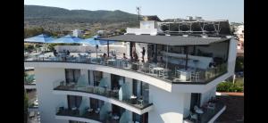 a white building with a balcony with tables and chairs at Blue Eye Hotel in Ksamil